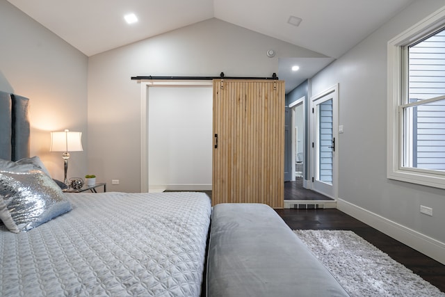 bedroom featuring a barn door, dark hardwood / wood-style floors, and vaulted ceiling