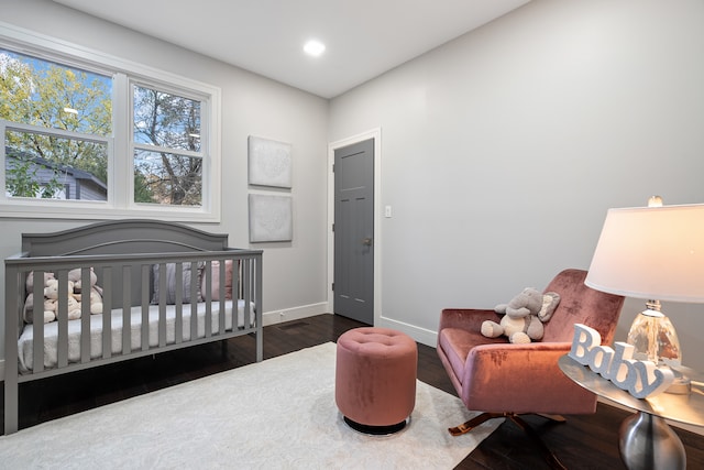 bedroom featuring a nursery area and dark hardwood / wood-style floors