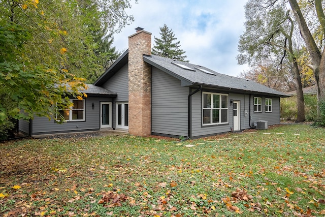 rear view of property featuring central air condition unit and a lawn