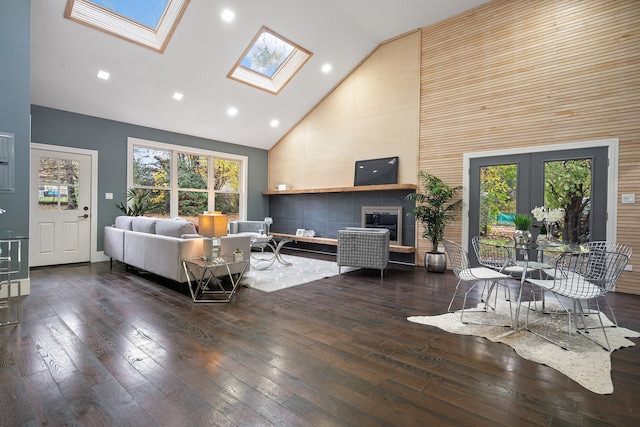 living room featuring dark hardwood / wood-style flooring, high vaulted ceiling, and a skylight