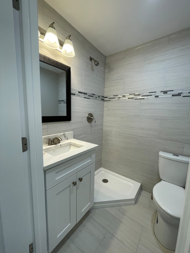 bathroom with toilet, vanity, tile walls, and walk in shower