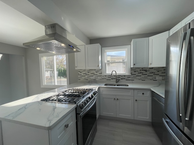 kitchen featuring white cabinetry, sink, wall chimney range hood, kitchen peninsula, and appliances with stainless steel finishes