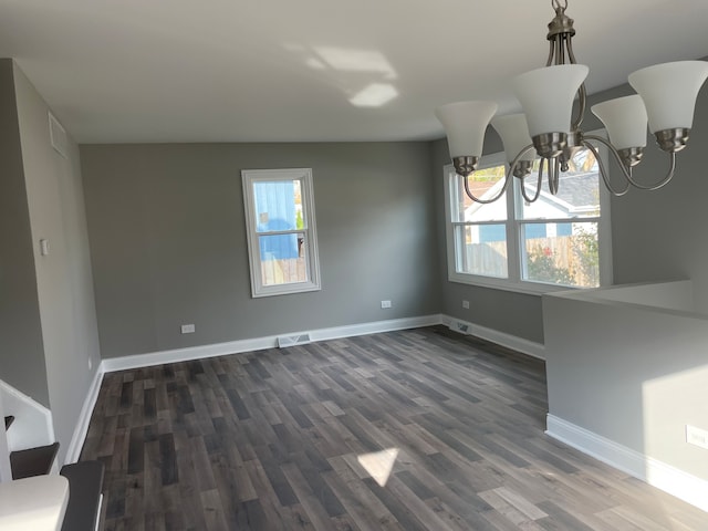 unfurnished dining area featuring dark hardwood / wood-style floors, an inviting chandelier, and a wealth of natural light