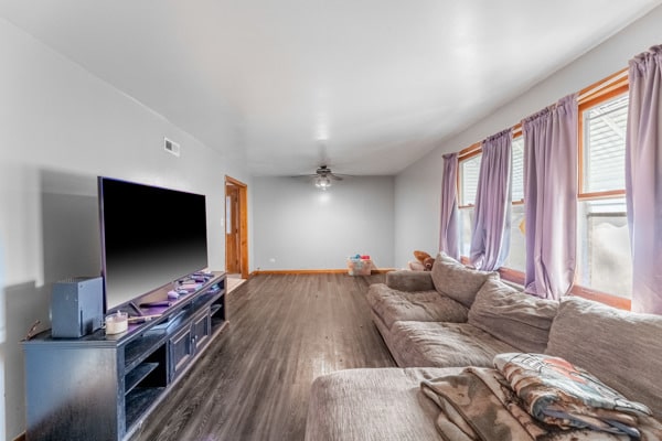 living room featuring ceiling fan and dark wood-type flooring