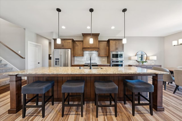 kitchen with a kitchen bar, light hardwood / wood-style flooring, and stainless steel appliances