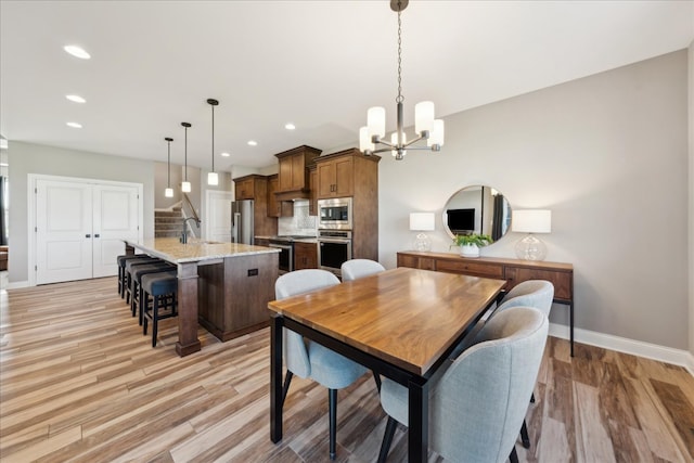 dining space with a chandelier, sink, and light hardwood / wood-style flooring