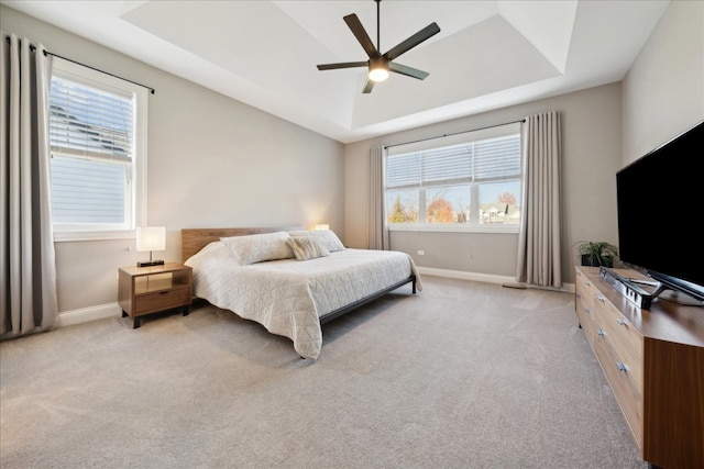 carpeted bedroom with a tray ceiling and ceiling fan