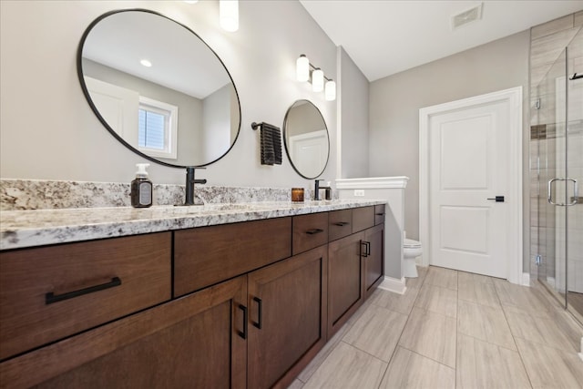 bathroom featuring tile patterned flooring, vanity, toilet, and a shower with shower door