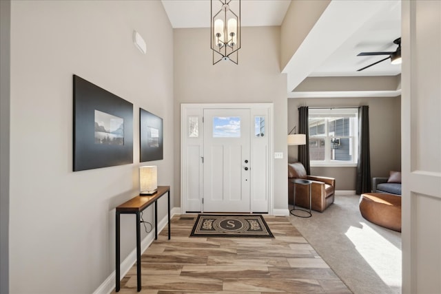 carpeted foyer entrance featuring ceiling fan with notable chandelier