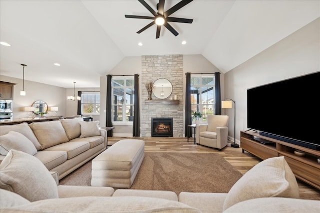 living room featuring ceiling fan with notable chandelier, light hardwood / wood-style floors, lofted ceiling, and a fireplace