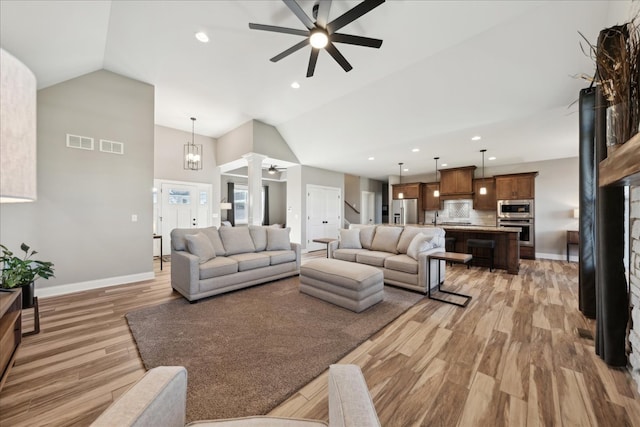 living room featuring high vaulted ceiling, wood-type flooring, and ceiling fan with notable chandelier