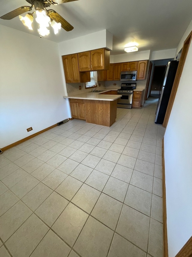 kitchen featuring kitchen peninsula, ceiling fan, light tile patterned floors, and appliances with stainless steel finishes