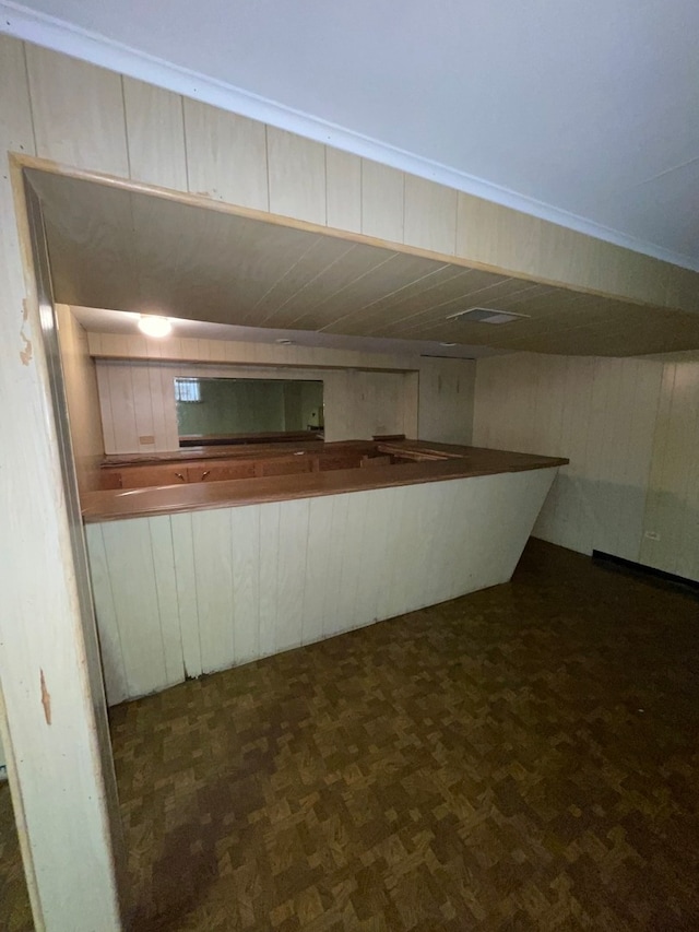 basement featuring dark parquet flooring and wooden walls