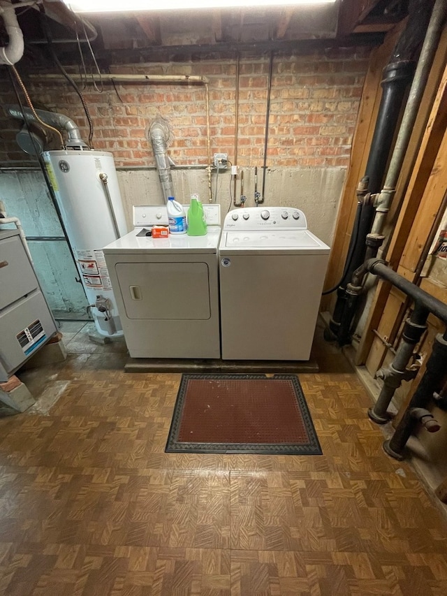 laundry area featuring brick wall, dark parquet flooring, washing machine and dryer, and water heater