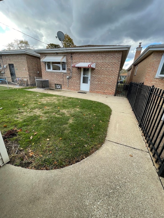 back of house featuring central AC unit and a lawn