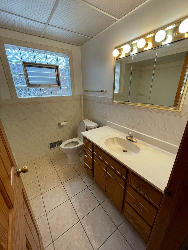 bathroom with tile patterned floors, vanity, tile walls, and toilet