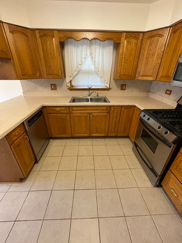 kitchen with decorative backsplash, sink, light tile patterned floors, and stainless steel appliances