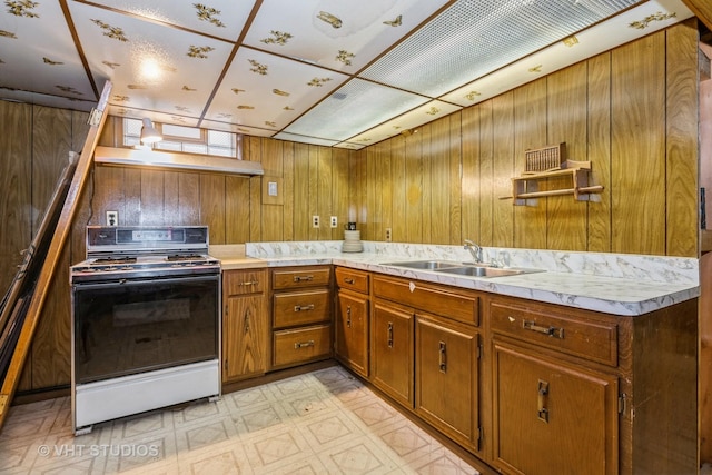 kitchen featuring white range with electric cooktop, wood walls, and sink