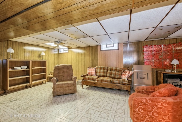 living room with a paneled ceiling and wooden walls