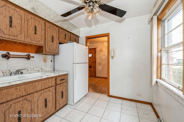 kitchen featuring light tile patterned flooring, sink, ceiling fan, tasteful backsplash, and white fridge