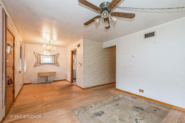 unfurnished room with ceiling fan with notable chandelier and light hardwood / wood-style floors