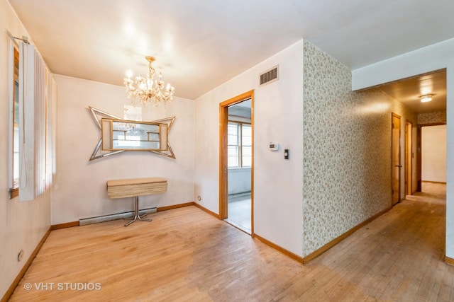 corridor featuring wood-type flooring, baseboard heating, and a notable chandelier