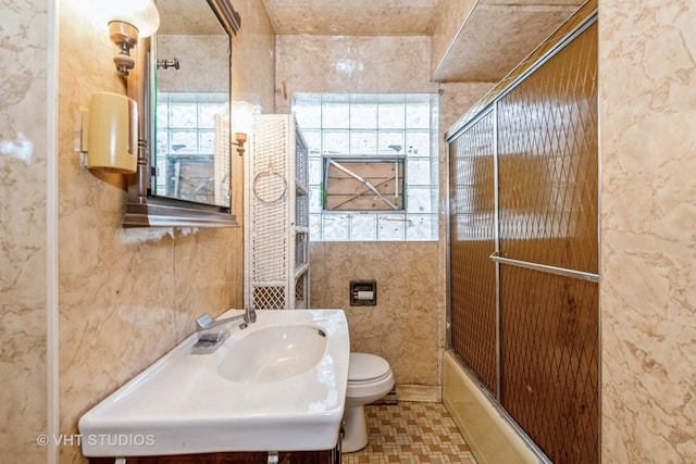 full bathroom featuring sink, tile patterned flooring, bath / shower combo with glass door, and toilet