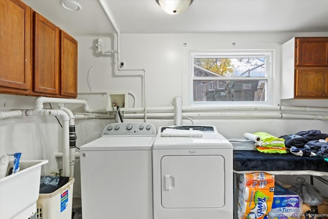 clothes washing area featuring separate washer and dryer, cabinet space, and a sink