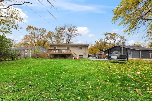 rear view of property featuring a trampoline, stairs, a fenced backyard, a deck, and a yard