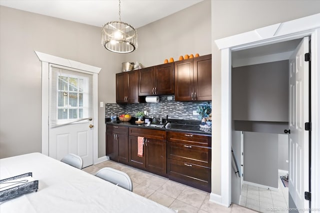 kitchen featuring an inviting chandelier, a sink, dark brown cabinets, pendant lighting, and tasteful backsplash