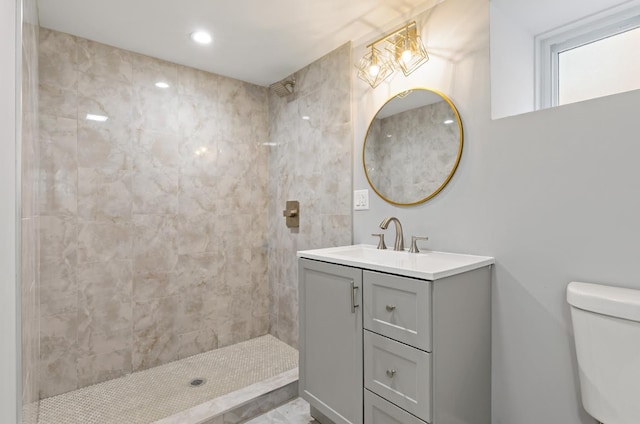 bathroom featuring a tile shower, vanity, and toilet