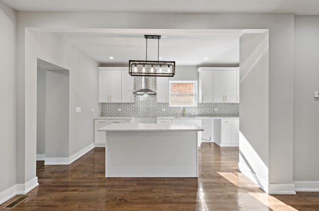 kitchen featuring dark hardwood / wood-style flooring, white cabinets, and wall chimney range hood