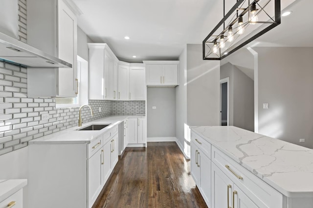 kitchen with white cabinets, wall chimney exhaust hood, dark hardwood / wood-style floors, and sink