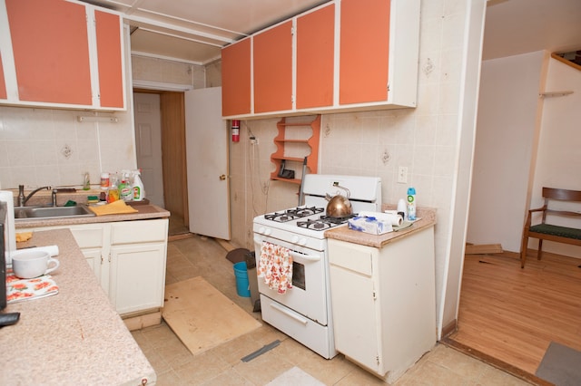 kitchen featuring light hardwood / wood-style flooring, tile walls, gas range gas stove, and sink