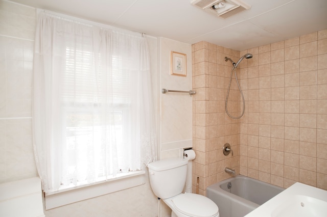 bathroom featuring tiled shower / bath combo and toilet