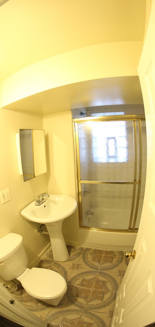 bathroom with tile patterned flooring, toilet, and enclosed tub / shower combo