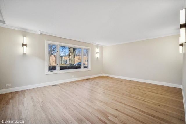 spare room featuring ornamental molding and light wood-type flooring