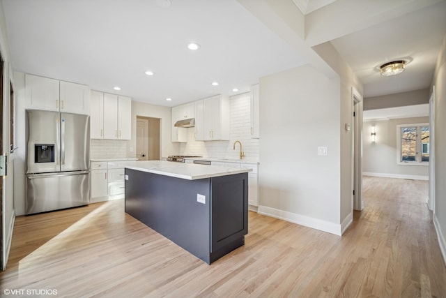 kitchen with white cabinetry, a center island, stainless steel appliances, tasteful backsplash, and light hardwood / wood-style floors