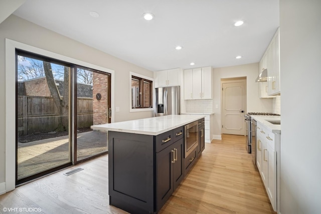 kitchen featuring white cabinets, a kitchen island, light hardwood / wood-style floors, and appliances with stainless steel finishes