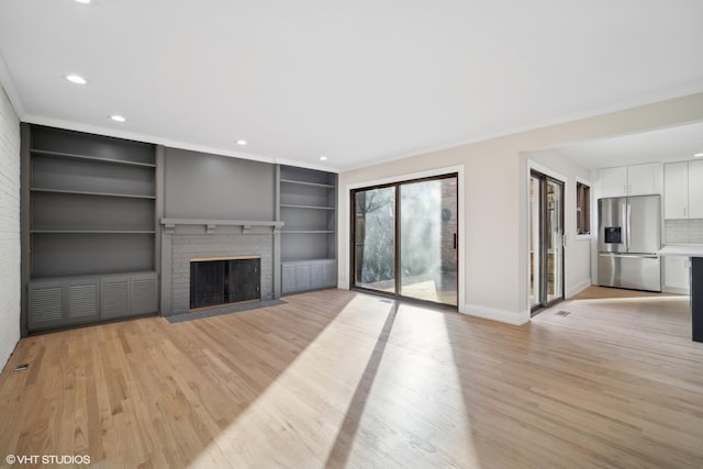 unfurnished living room with built in shelves, light hardwood / wood-style floors, ornamental molding, and a fireplace