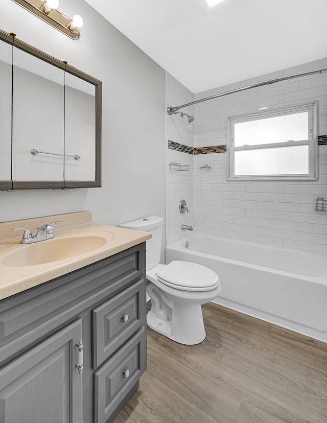 full bathroom with tiled shower / bath, vanity, wood-type flooring, and toilet