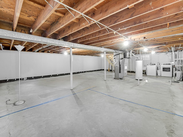 basement with heating unit, water heater, and washer and dryer