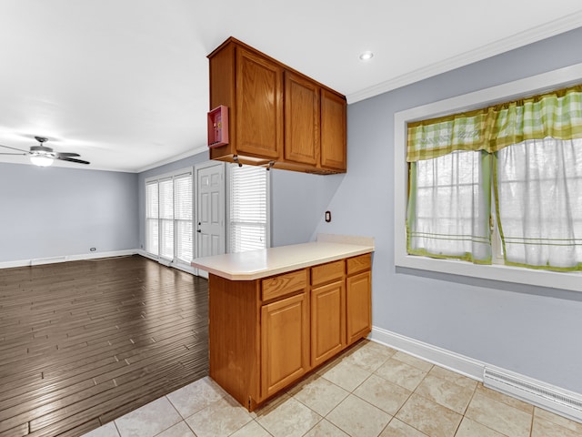 kitchen featuring kitchen peninsula, light wood-type flooring, ceiling fan, and crown molding