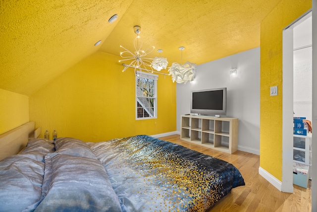 bedroom with a textured ceiling, wood-type flooring, vaulted ceiling, and an inviting chandelier