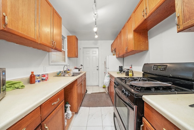 kitchen with light tile patterned flooring, black range with gas stovetop, rail lighting, and sink