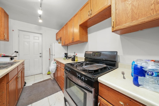 kitchen with gas stove, sink, and rail lighting