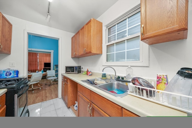 kitchen featuring rail lighting, black range, light tile patterned floors, and sink