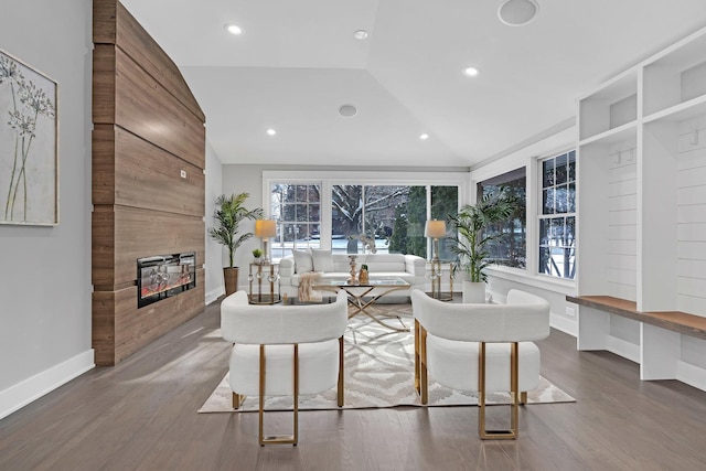 living room featuring vaulted ceiling, plenty of natural light, a tiled fireplace, and hardwood / wood-style floors