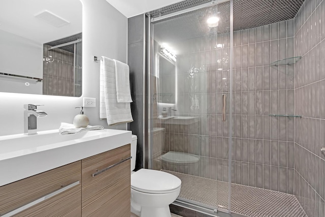 bathroom featuring a shower with door, toilet, and vanity