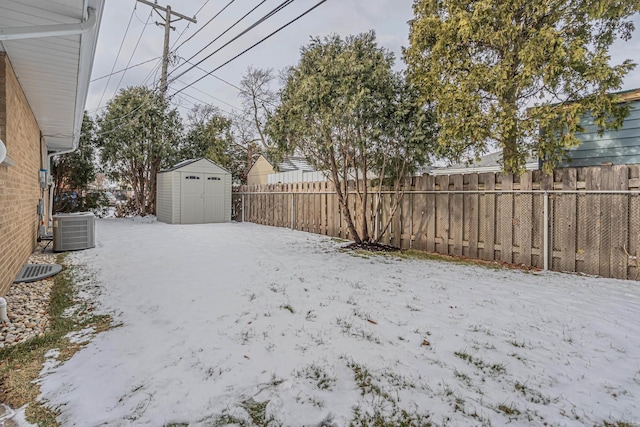 yard layered in snow featuring a storage shed and cooling unit